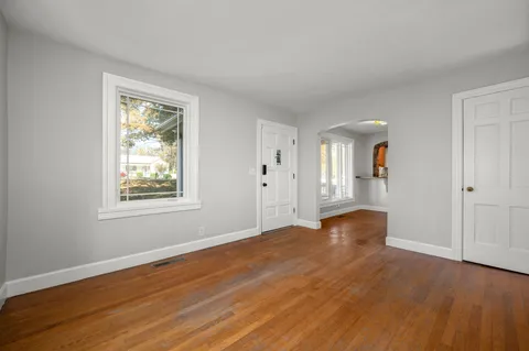 a view of an empty room with wooden floor and a window