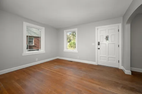 a view of an empty room with window and wooden floor