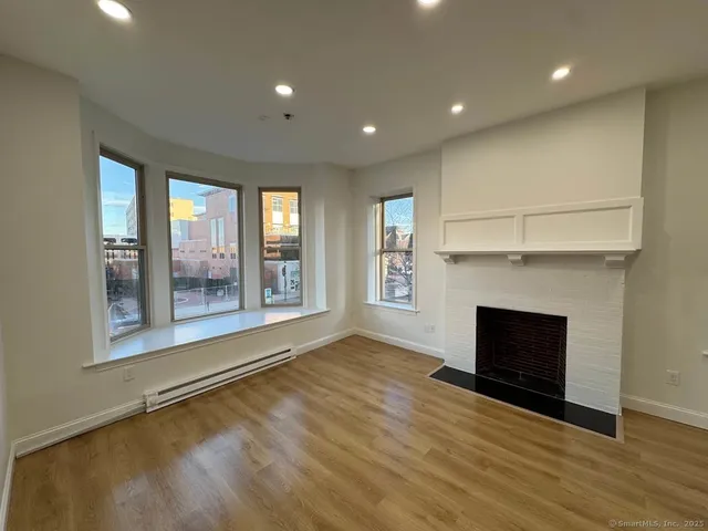 an empty room with wooden floor fireplace and windows