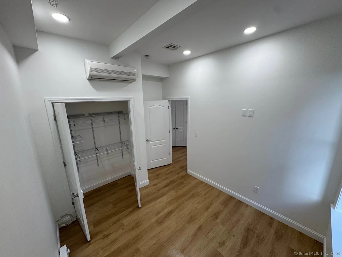 160 Main Street, Unit 2B New Britain, CT 06051 - Photo 4 of 9 an empty room with wooden floor and cabinet