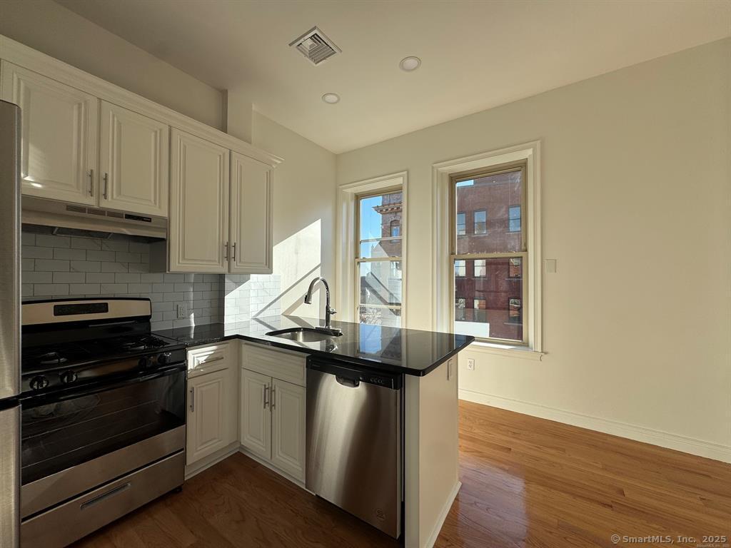 160 Main Street, Unit 2B New Britain, CT 06051 - Photo 8 of 9 a kitchen with stainless steel appliances granite countertop a sink a stove and a wooden floors