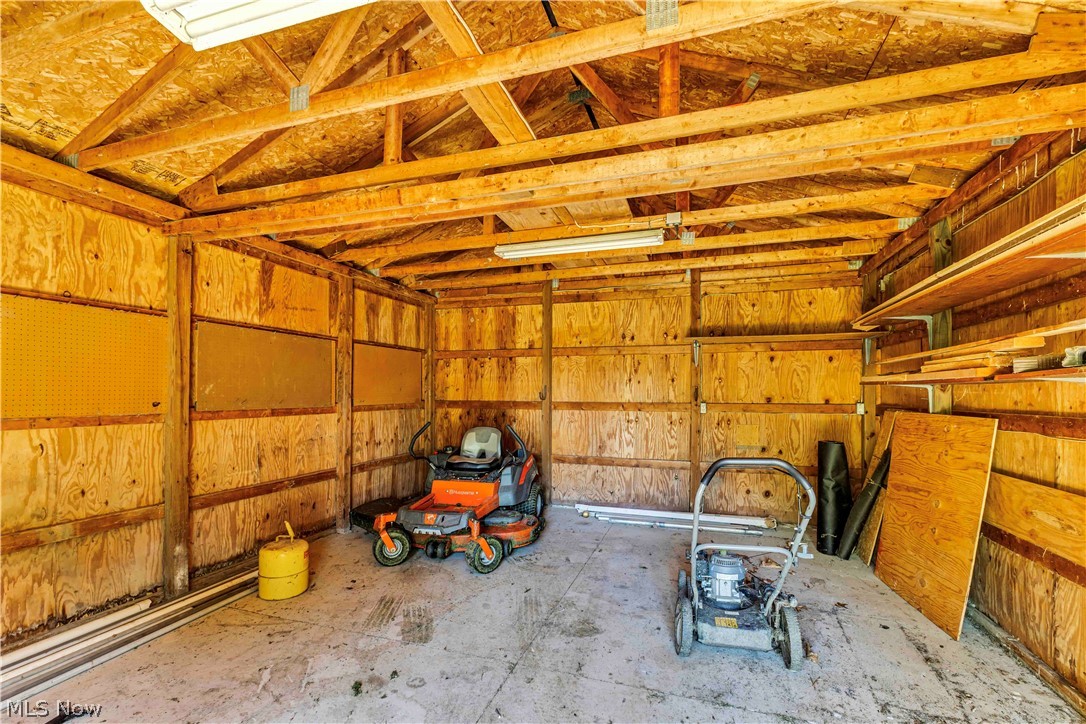 6635 Taylor Road Painesville, OH 44077 - Photo 40 of 41 Utility shed interior featuring exposed wood-beam ceiling, plywood wall construction, concrete flooring, and built-in shelving