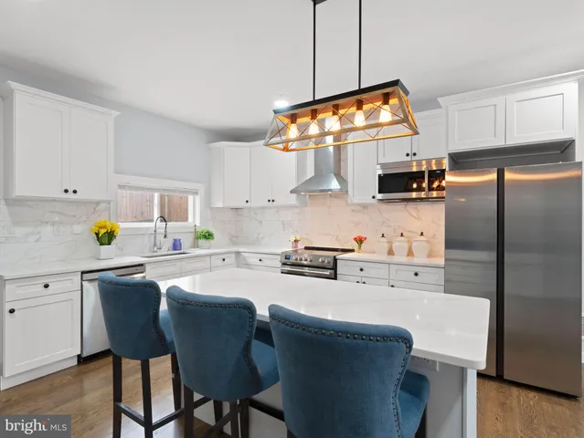 a kitchen with stainless steel appliances granite countertop a sink a stove a refrigerator cabinets and chairs