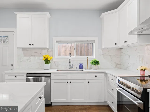 a kitchen with stainless steel appliances granite countertop a sink a stove a refrigerator cabinets and chairs