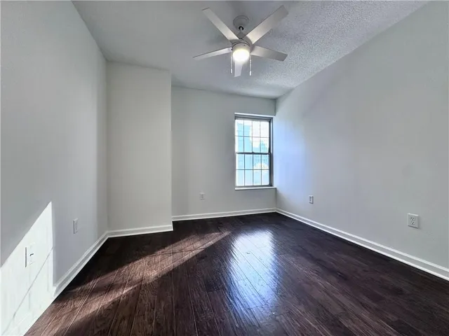 an empty room with wooden floor ceiling fan and windows
