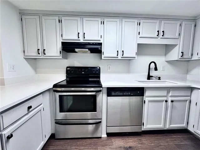 a kitchen with granite countertop white cabinets and stainless steel appliances
