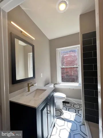 a bathroom with a granite countertop sink toilet a mirror and shower