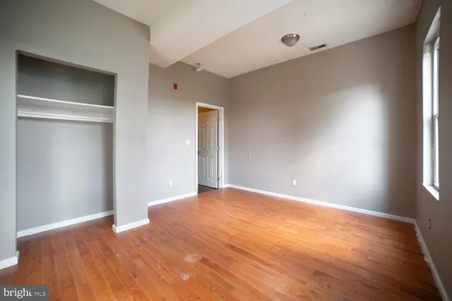 a view of an empty room with wooden floor and a window