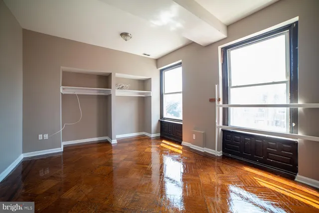 a view of an empty room with a window and wooden floor