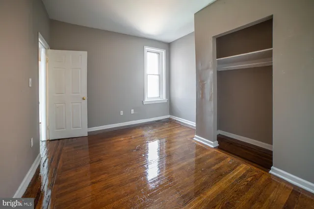 an empty room with wooden floor & closet area