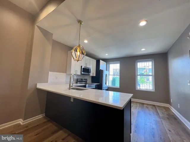 a large kitchen with granite countertop a sink window and wooden floor
