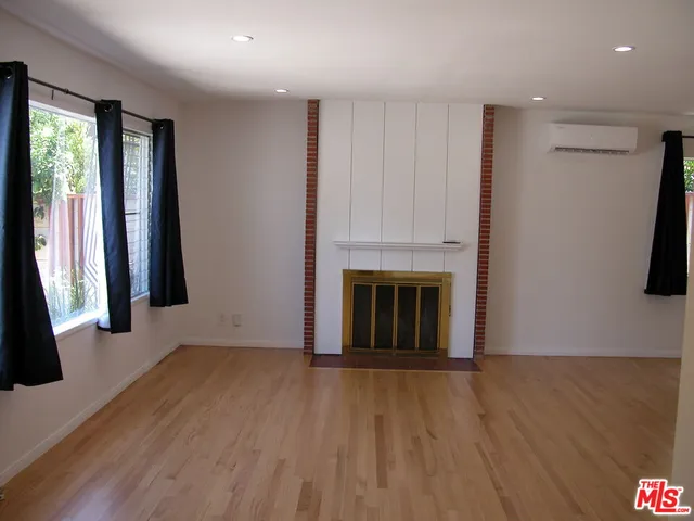 an empty room with wooden floor and a fireplace
