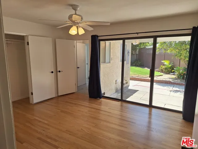 a view of empty room with wooden floor and fan