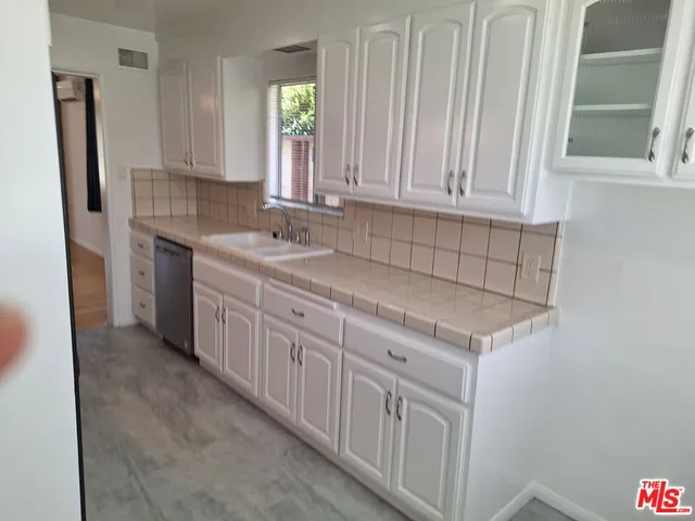 a kitchen with granite countertop white cabinets and sink
