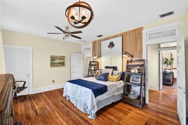 a bedroom with a bed and dresser with wooden floor