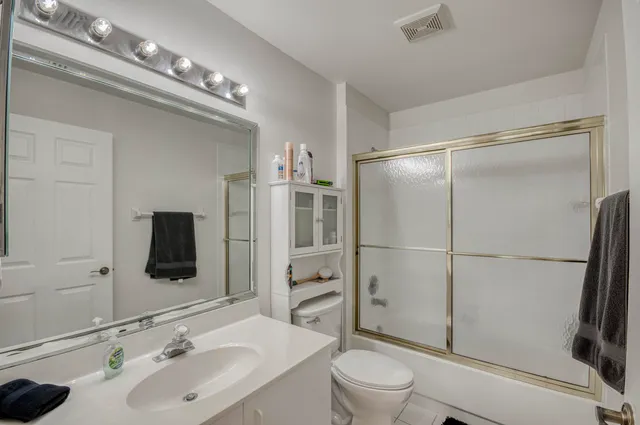 a bathroom with a toilet a sink a mirror and shower