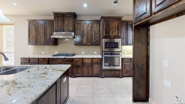 a kitchen with kitchen island granite countertop a sink stove and refrigerator