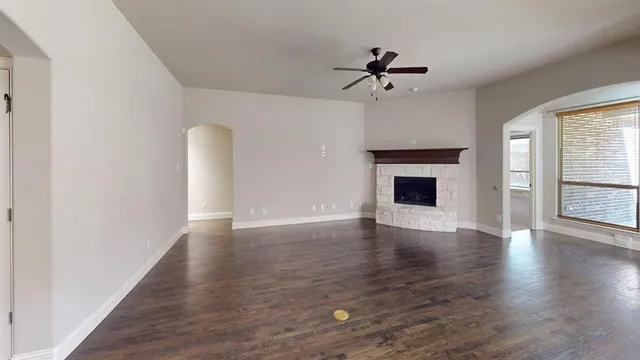 an empty room with wooden floor fireplace and windows
