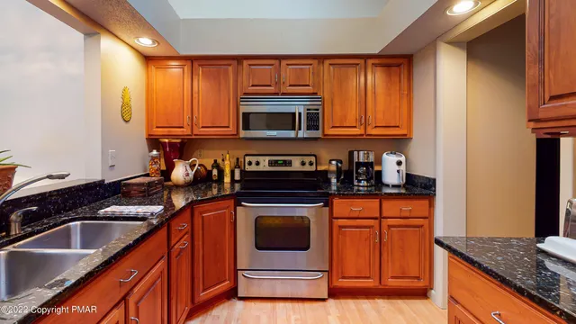 a kitchen with granite countertop a sink stainless steel appliances and cabinets