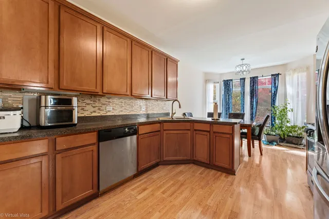 a kitchen with stainless steel appliances granite countertop a stove top oven a sink dishwasher a dining table and chairs with wooden floor