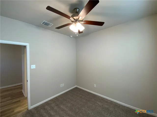 an empty room with windows and fan