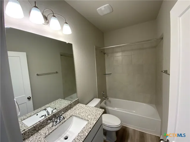 a bathroom with a granite countertop sink toilet and shower