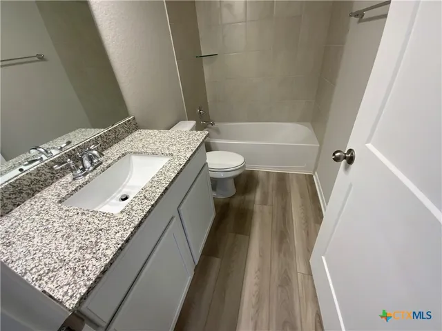 a bathroom with a granite countertop sink and toilet