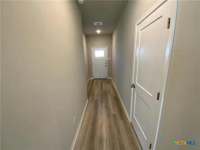 a view of a hallway with wooden floor and a bathroom