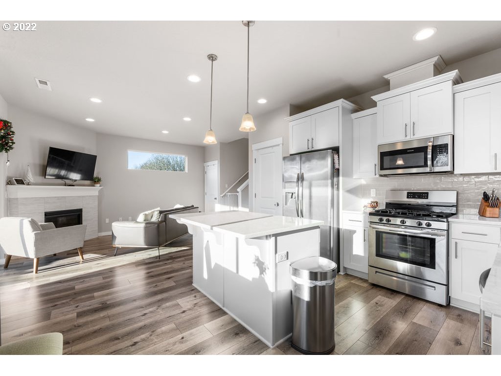 2620 South 12th Court Ridgefield, WA 98642 - Photo 10 of 20 a kitchen with stainless steel appliances kitchen island granite countertop a stove a sink a microwave a refrigerator and white cabinets with wooden floors