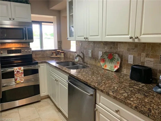 a kitchen with stainless steel appliances granite countertop a stove a sink and a microwave