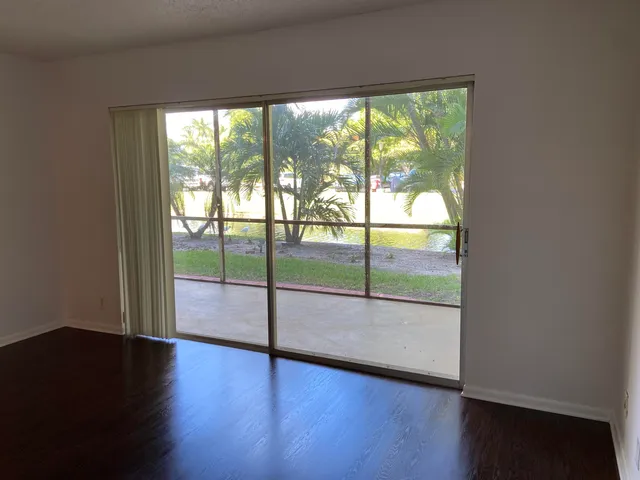 a view of an empty room with wooden floor and windows