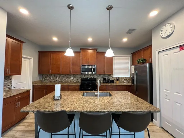 a kitchen with stainless steel appliances granite countertop a kitchen island and chairs