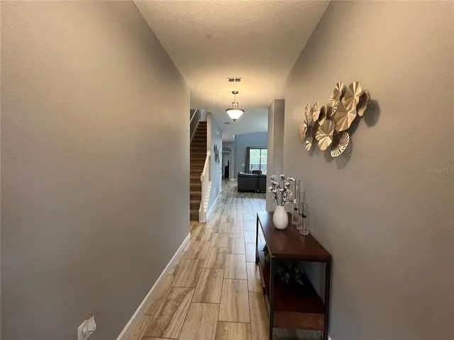 a view of a hallway with wooden floor and a bathroom
