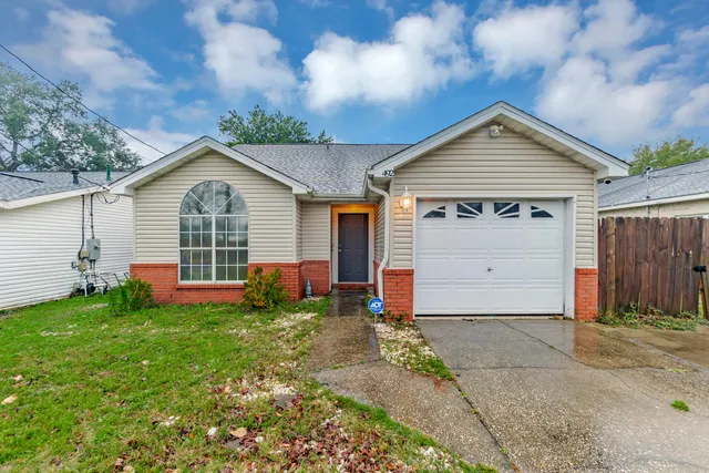 a view of a house with a small yard and a garage