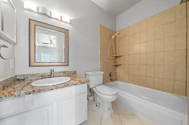 a bathroom with a granite countertop bathtub sink vanity mirror and toilet