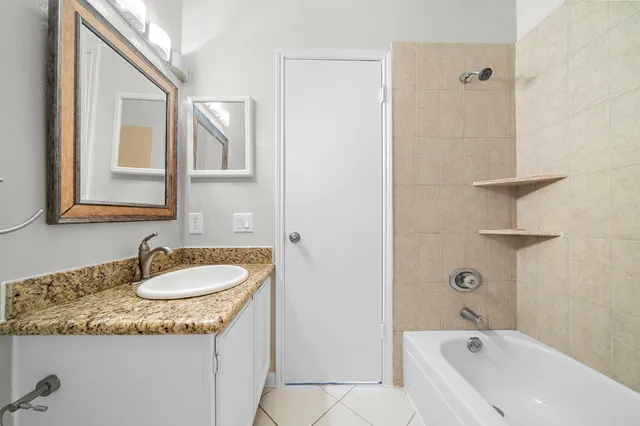a bathroom with a granite countertop sink mirror and a bathtub