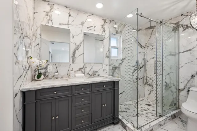 a bathroom with a granite countertop sink a toilet and shower