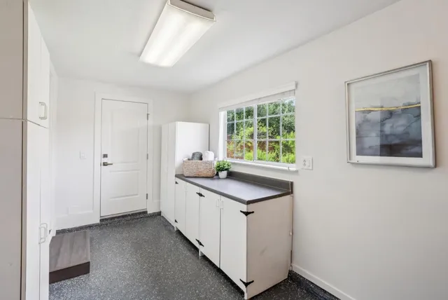 a kitchen with white cabinets and window