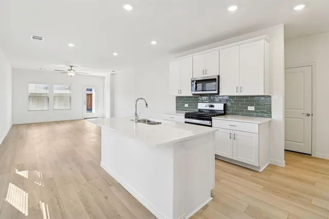 a kitchen with stainless steel appliances a sink a stove top oven a counter space and cabinets