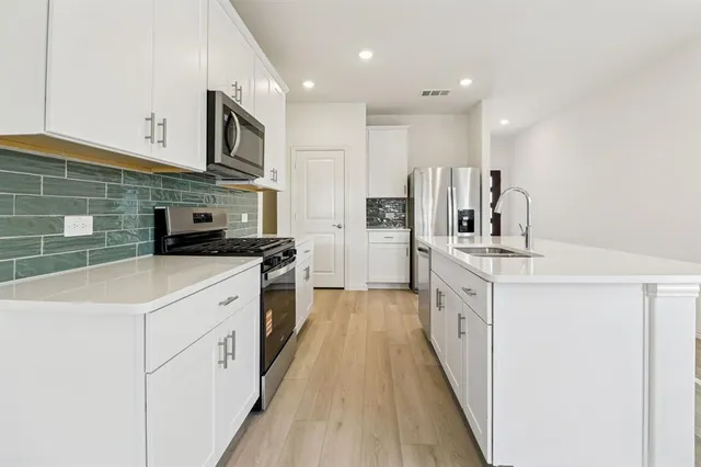 a kitchen with white cabinets sink and stainless steel appliances