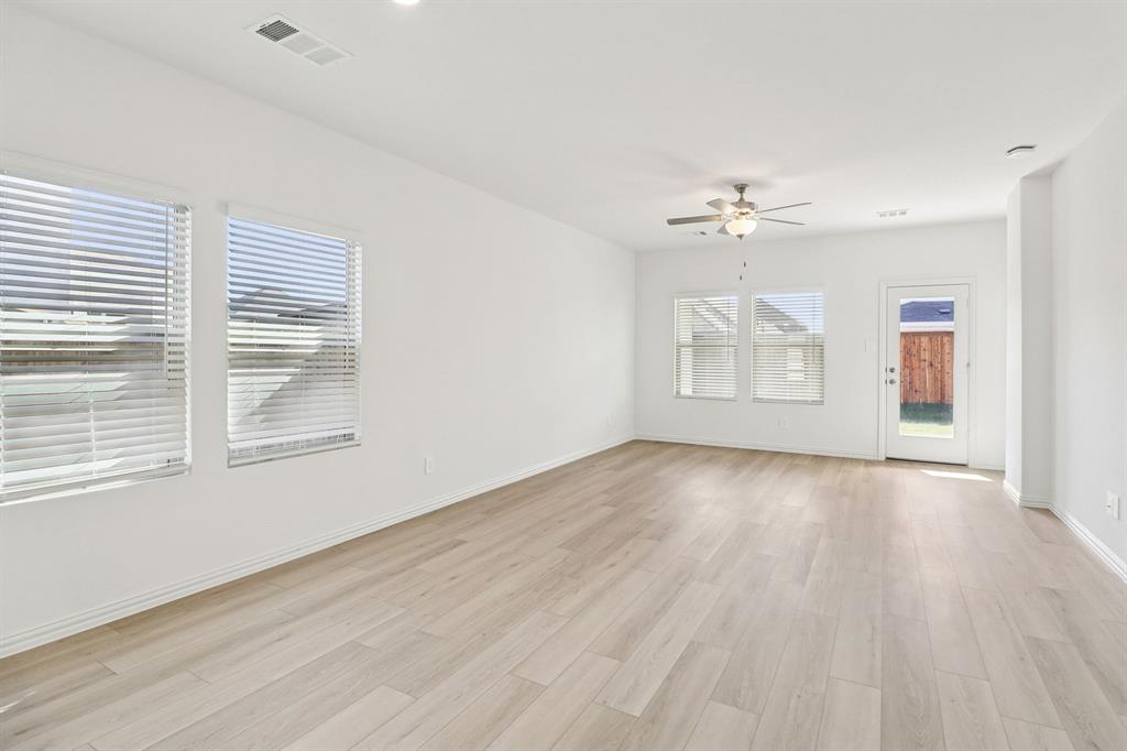 1708 Arches Road Anna, TX 75409 - Photo 5 of 21 an empty room with wooden floor chandelier fan and windows