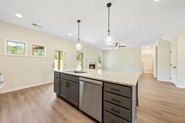 a kitchen with stainless steel appliances granite countertop a sink a island a stove and a wooden floors