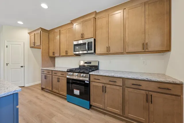 a kitchen with stainless steel appliances granite countertop a stove a sink and a microwave