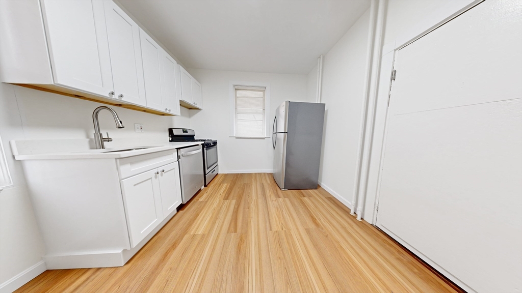 a kitchen with a sink a refrigerator freezer a stove and white cabinets