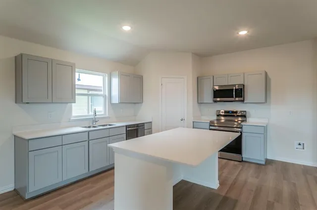 a view of kitchen with kitchen island wooden floor and center island