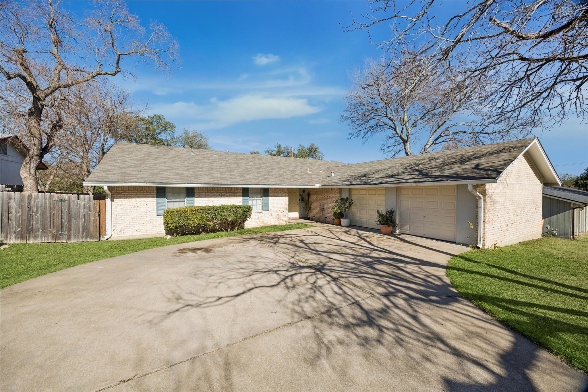 Single story home featuring brick siding, driveway, an attached garage, and roof with shingles
