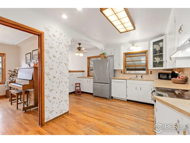 a kitchen with stainless steel appliances a stove top oven a refrigerator a sink dishwasher with wooden floor and cabinets