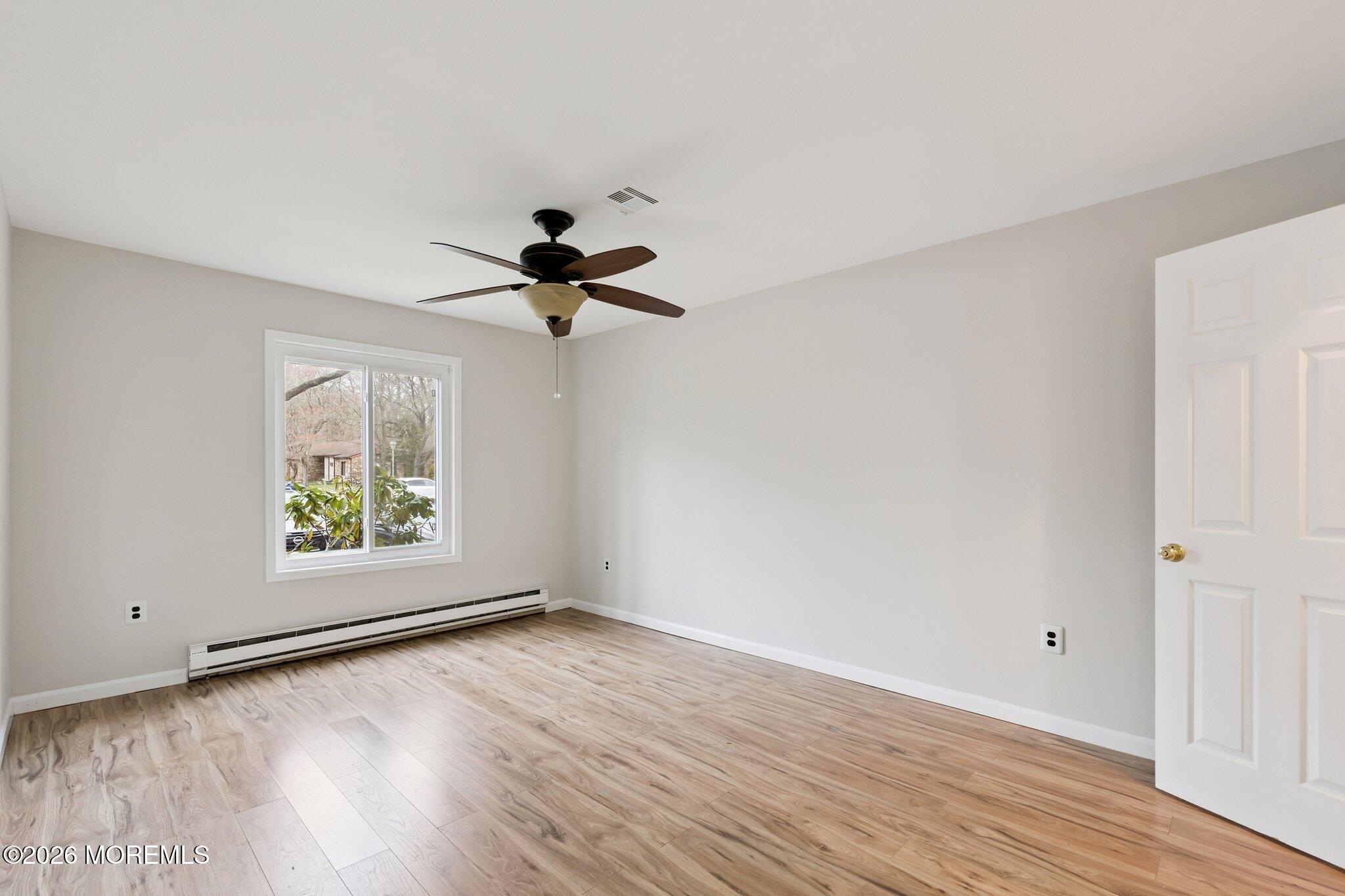 102 Arrowood Road, Unit B Manalapan, NJ 07726 - Photo 22 of 41 an empty room with wooden floor chandelier fan and windows