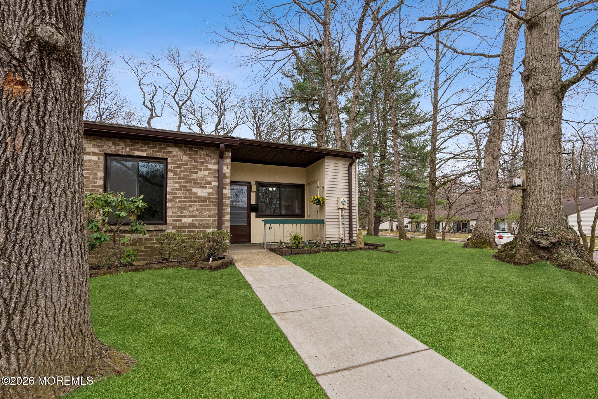 102 Arrowood Road, Unit B Manalapan, NJ 07726 - Photo 4 of 41 a view of a yard in front of a brick house with a large tree