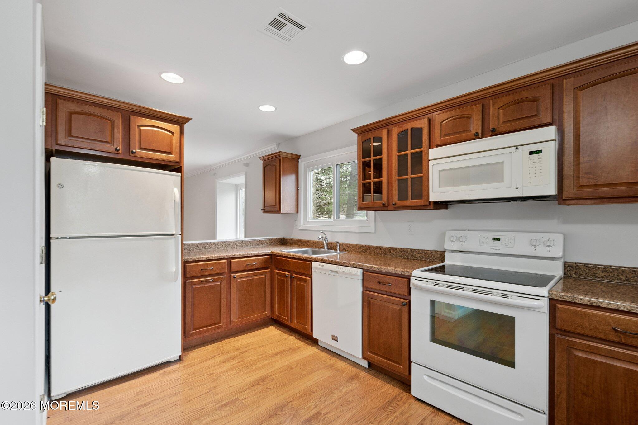 102 Arrowood Road, Unit B Manalapan, NJ 07726 - Photo 8 of 41 a kitchen with stainless steel appliances granite countertop a stove top oven a sink and dishwasher a refrigerator with wooden cabinets